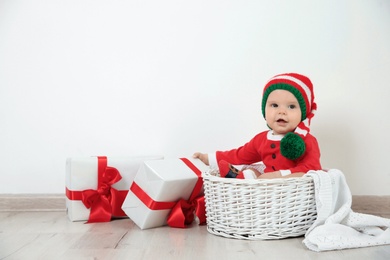 Photo of Cute little baby wearing Christmas costume in basket at home