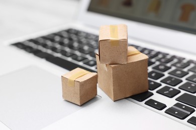 Photo of Internet shopping. Small cardboard boxes on laptop, closeup