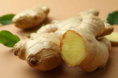 Photo of Fresh ginger and green leaves on light pale brown background, closeup