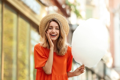 Emotional young woman with cotton candy outdoors