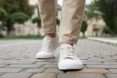 Photo of Man in stylish sneakers walking on city street, closeup