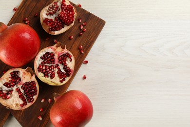 Photo of Flat lay composition with ripe pomegranates on white wooden table. Space for text