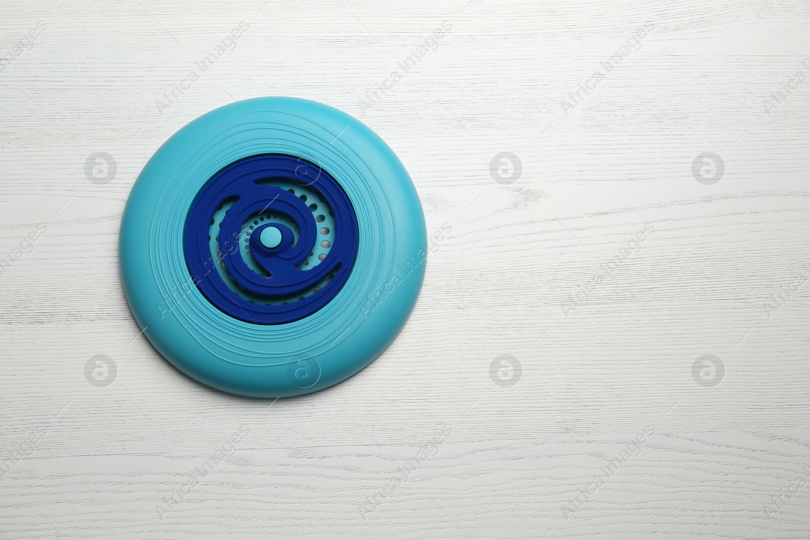 Photo of Blue plastic frisbee disk on white wooden background, top view. Space for text