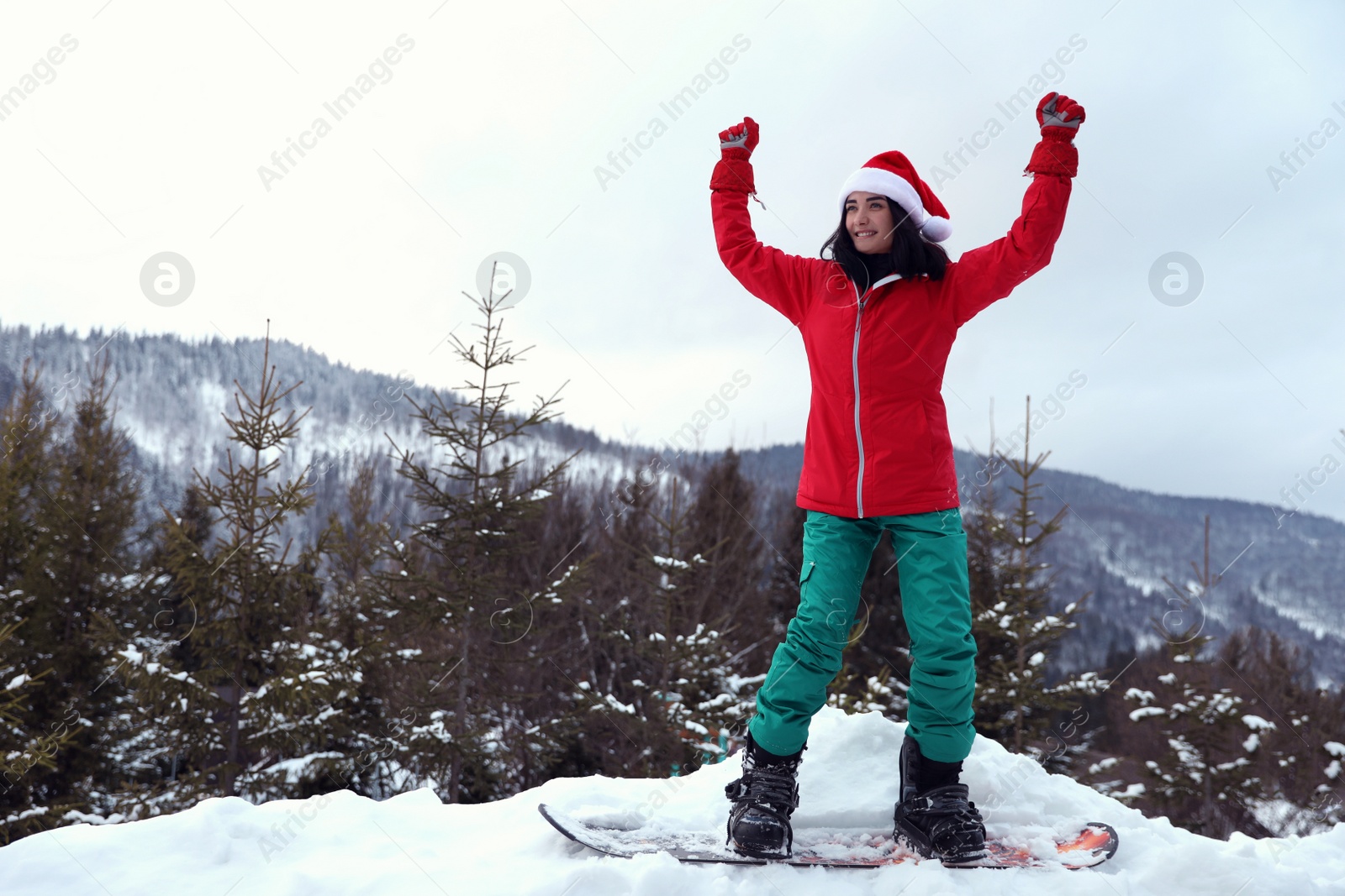 Photo of Young snowboarder wearing Santa hat on snowy hill. Winter vacation