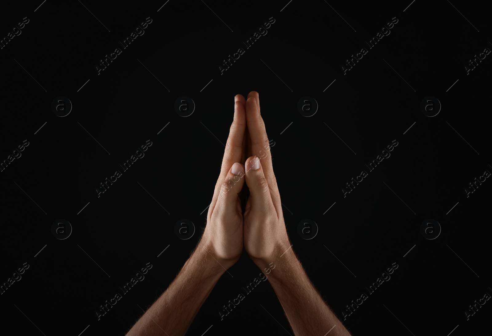 Photo of Man praying against black background, closeup view