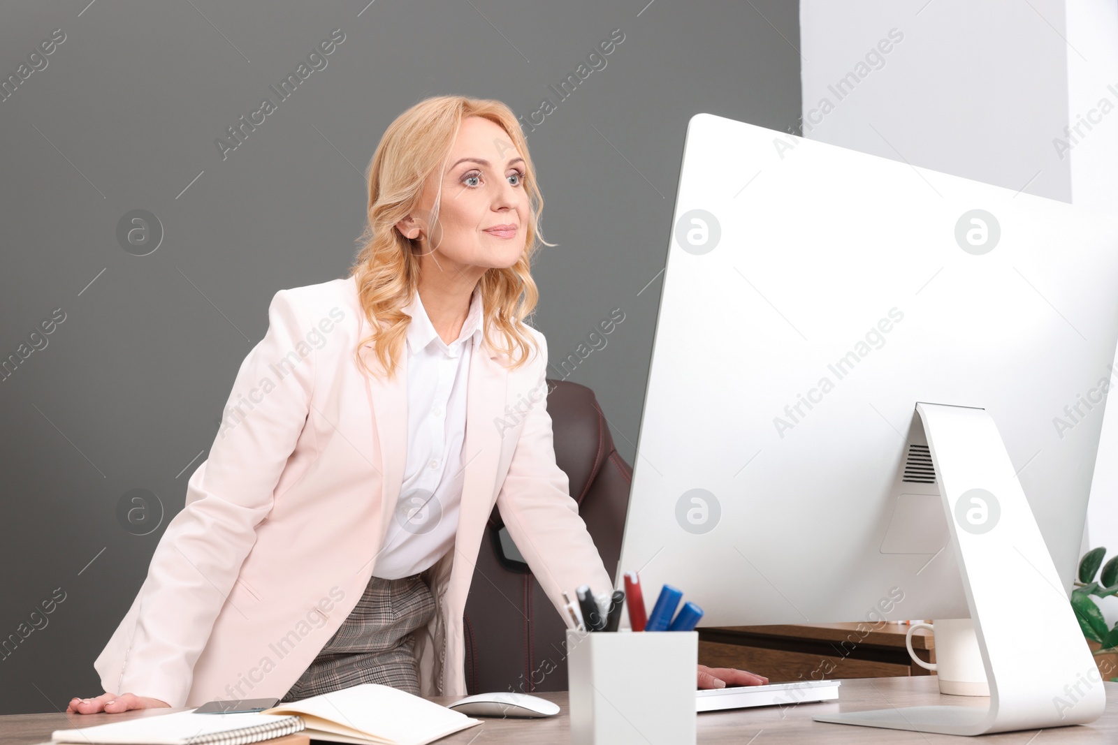 Photo of Happy lady boss working on computer in office. Successful businesswoman