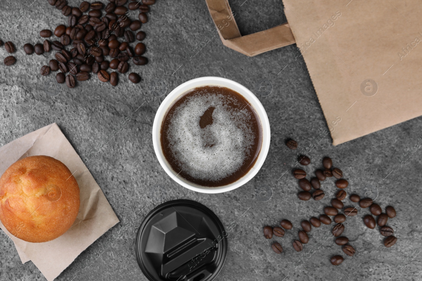 Photo of Coffee to go. Paper cup with tasty drink, muffin and beans on grey table, flat lay