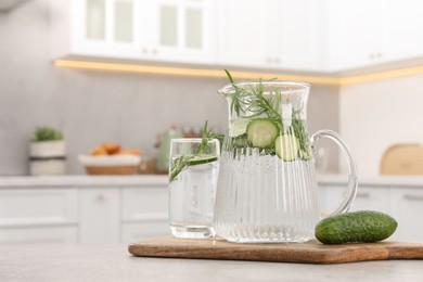 Refreshing cucumber water with rosemary and vegetable on table in kitchen. Space for text