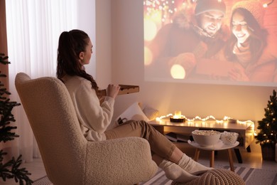 Woman with pizza watching romantic Christmas movie via video projector at home