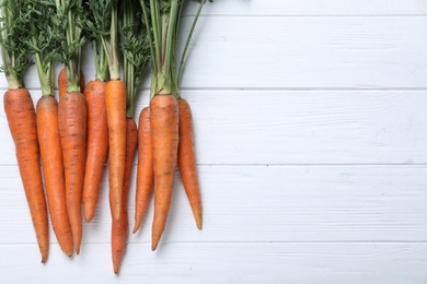 Ripe carrots on white wooden table, flat lay. Space for text