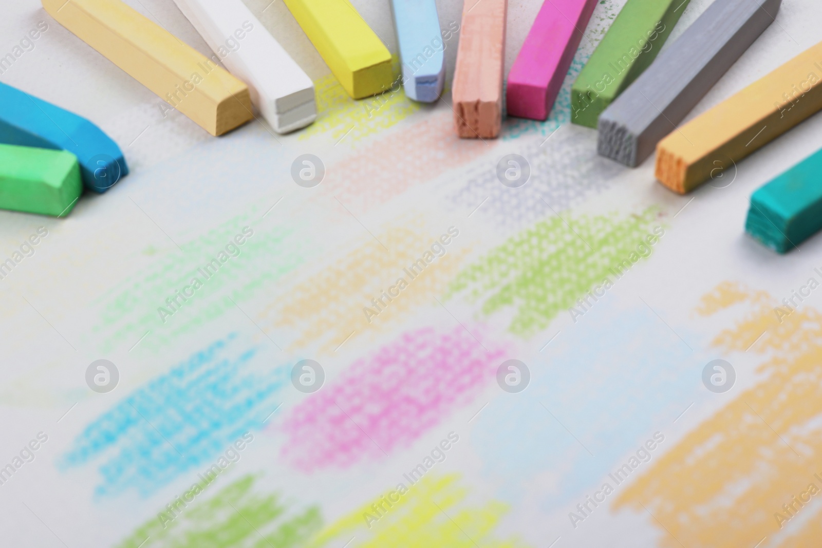 Photo of Colorful pastel chalks and scribbles on white background, closeup. Drawing materials