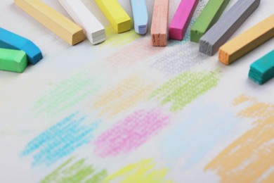 Photo of Colorful pastel chalks and scribbles on white background, closeup. Drawing materials