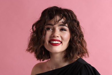 Portrait of beautiful young woman with wavy hairstyle on pink background