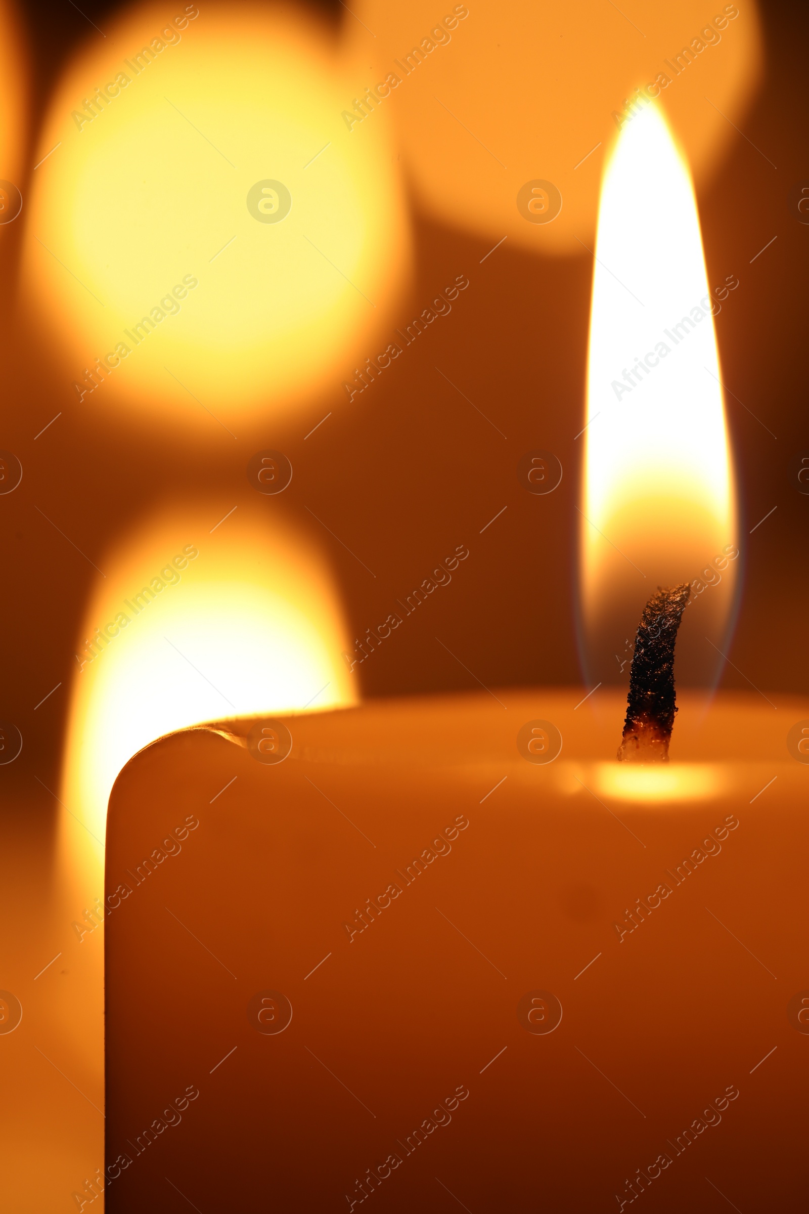 Photo of Burning wax candles on blurred background, closeup