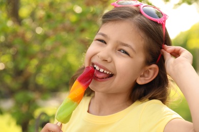 Cute little girl with delicious ice cream in park