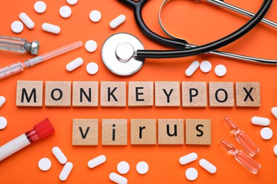 Photo of Flat lay composition with words Monkeypox Virus made of wooden squares and medical supplies on orange background