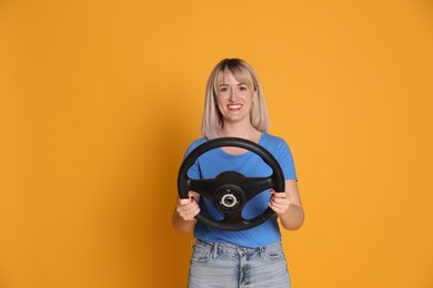 Photo of Happy woman with steering wheel on yellow background. Space for text