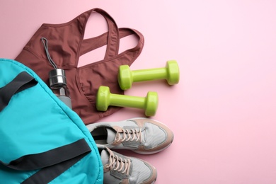 Photo of Flat lay composition with sportswear, gym bag and dumbbells on pink background, space for text