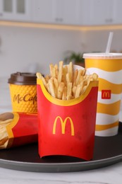 MYKOLAIV, UKRAINE - AUGUST 12, 2021: Two big portions of McDonald's French fries and drinks on marble table in kitchen