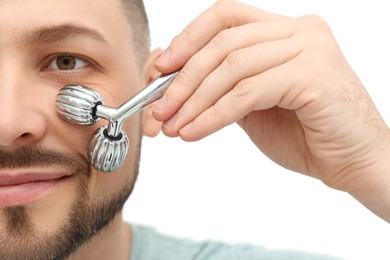 Photo of Man using metal facial roller on white background, closeup
