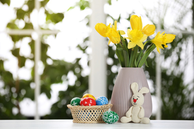 Photo of Festive composition with Easter eggs on table against blurred window, space for text