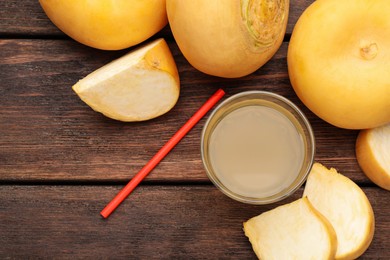 Photo of Glass of freshly made turnip juice on wooden table, flat lay