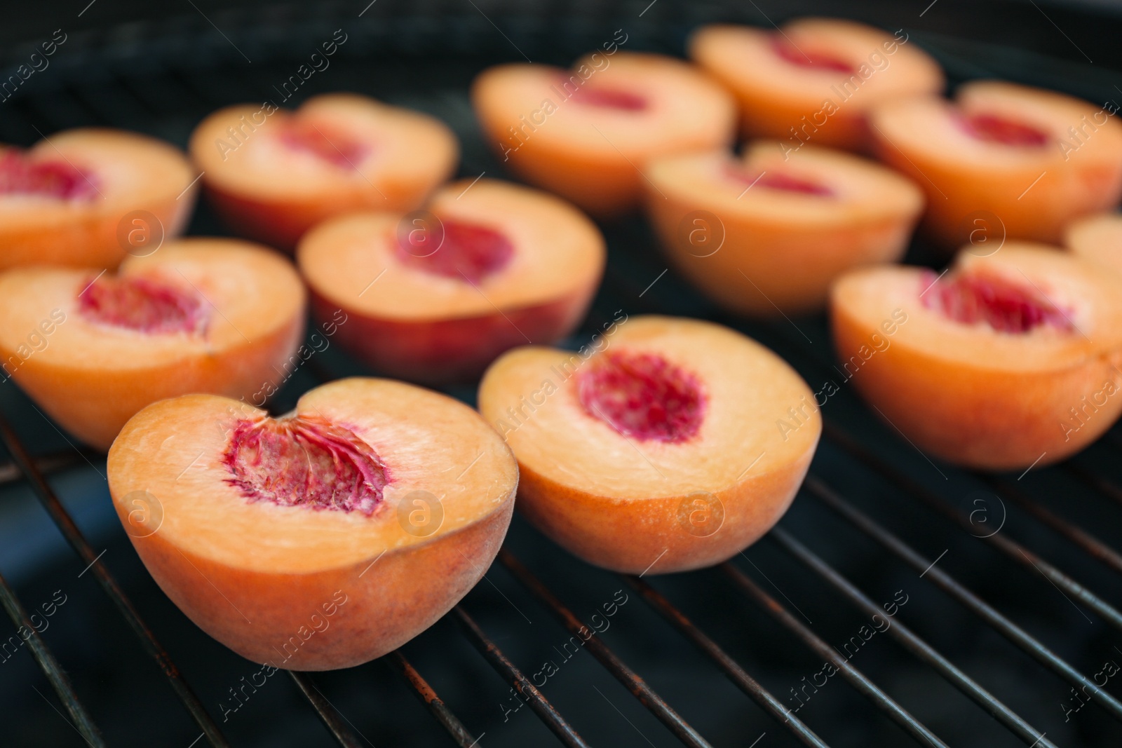 Photo of Modern grill with tasty cut peaches, closeup