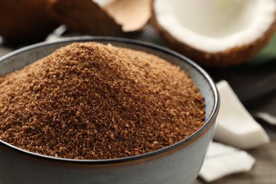 Natural coconut sugar in ceramic bowl on table, closeup