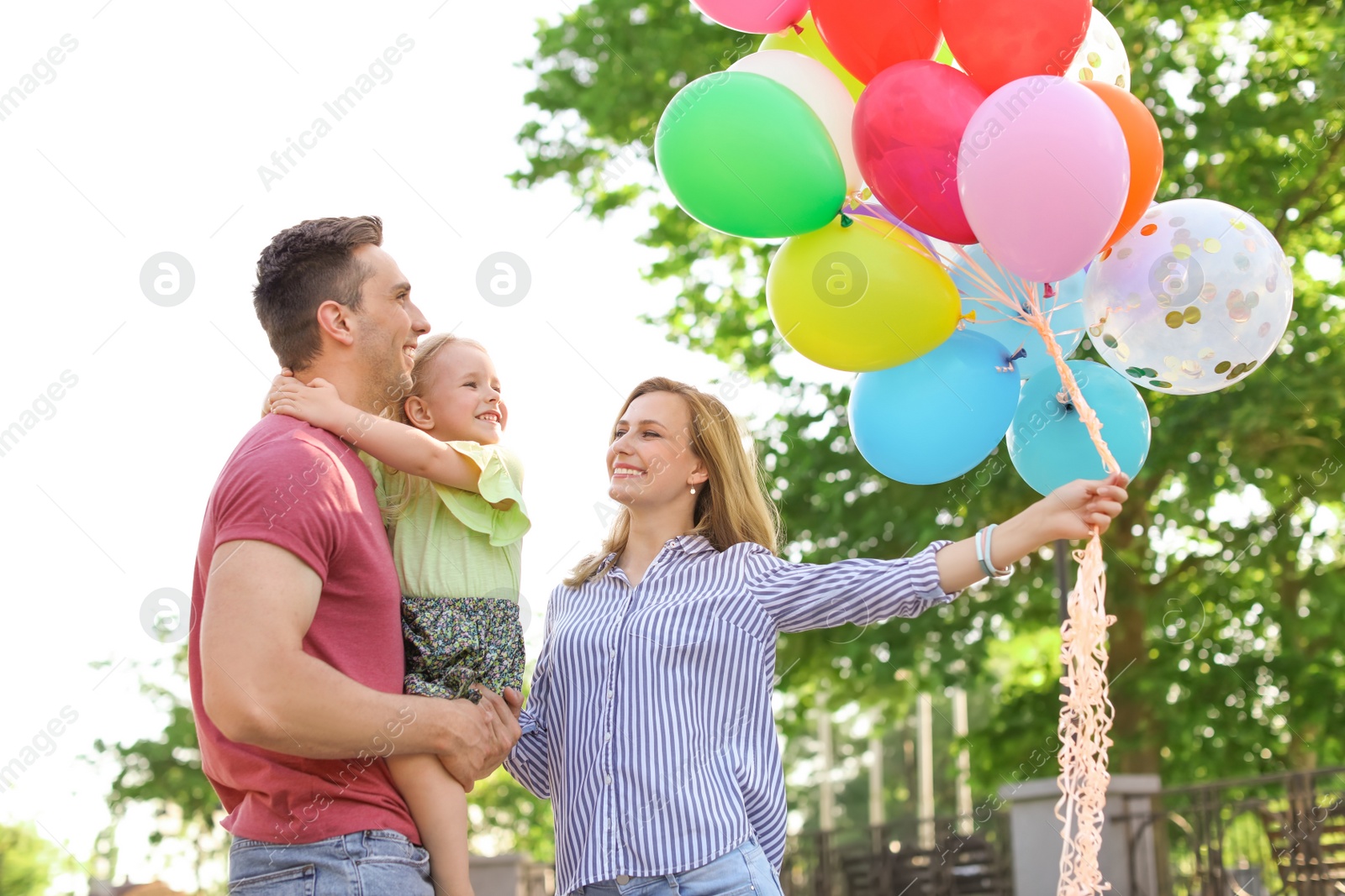 Photo of Happy family with colorful balloons outdoors on sunny day