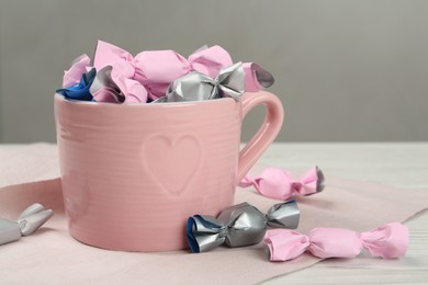 Photo of Candies in colorful wrappers on white wooden table