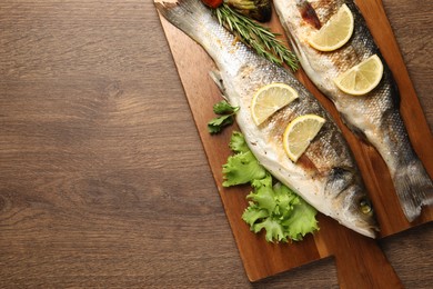 Photo of Delicious baked fish and vegetables on wooden table, top view. Space for text