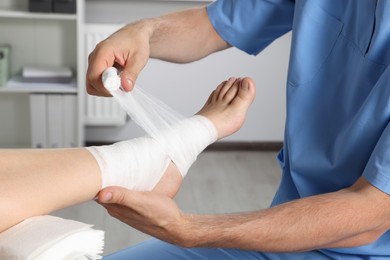 Photo of Doctor applying bandage onto patient's foot in hospital, closeup