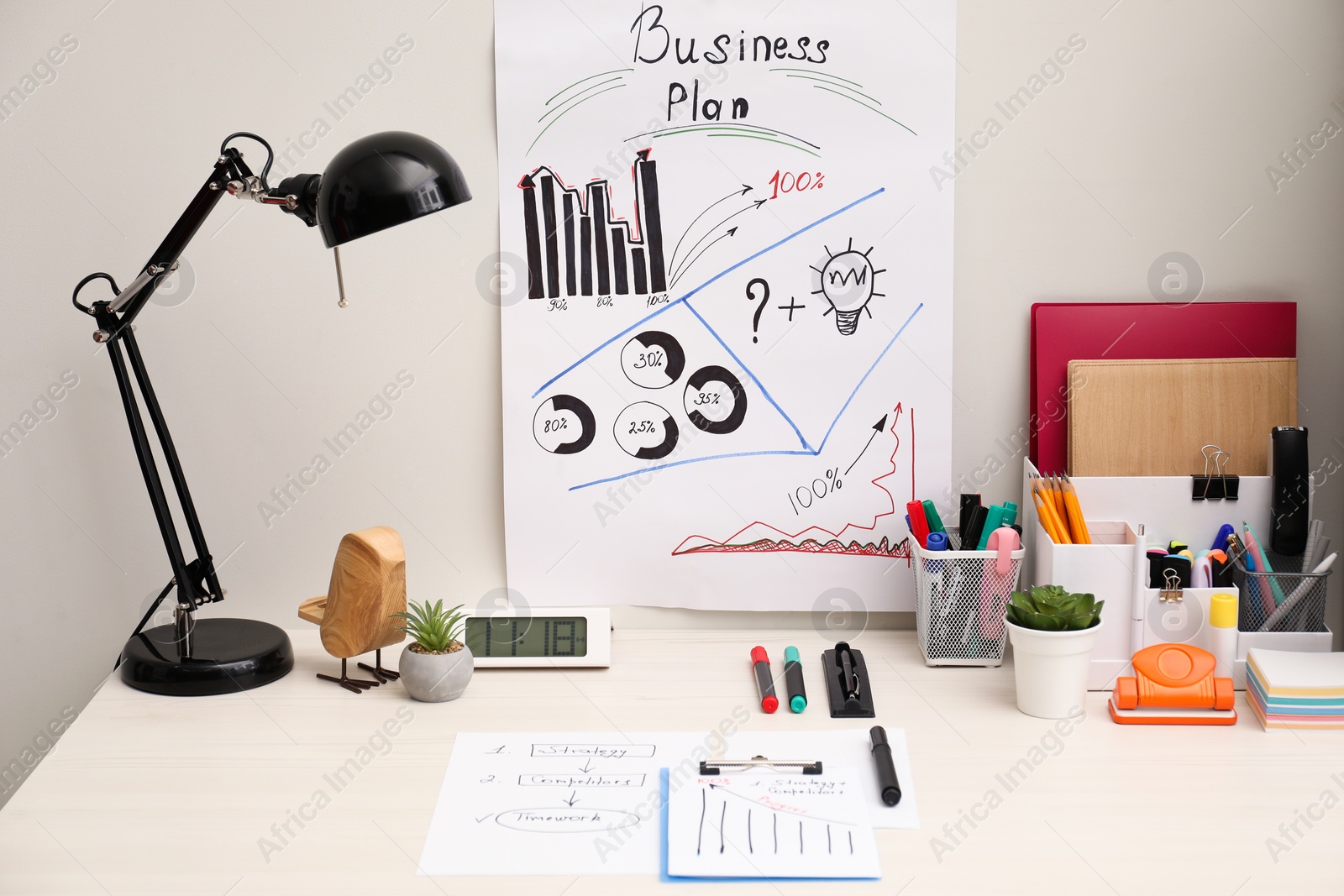 Photo of Business process planning and optimization. Workplace with plan, lamp, notebook and stationery on white wooden table