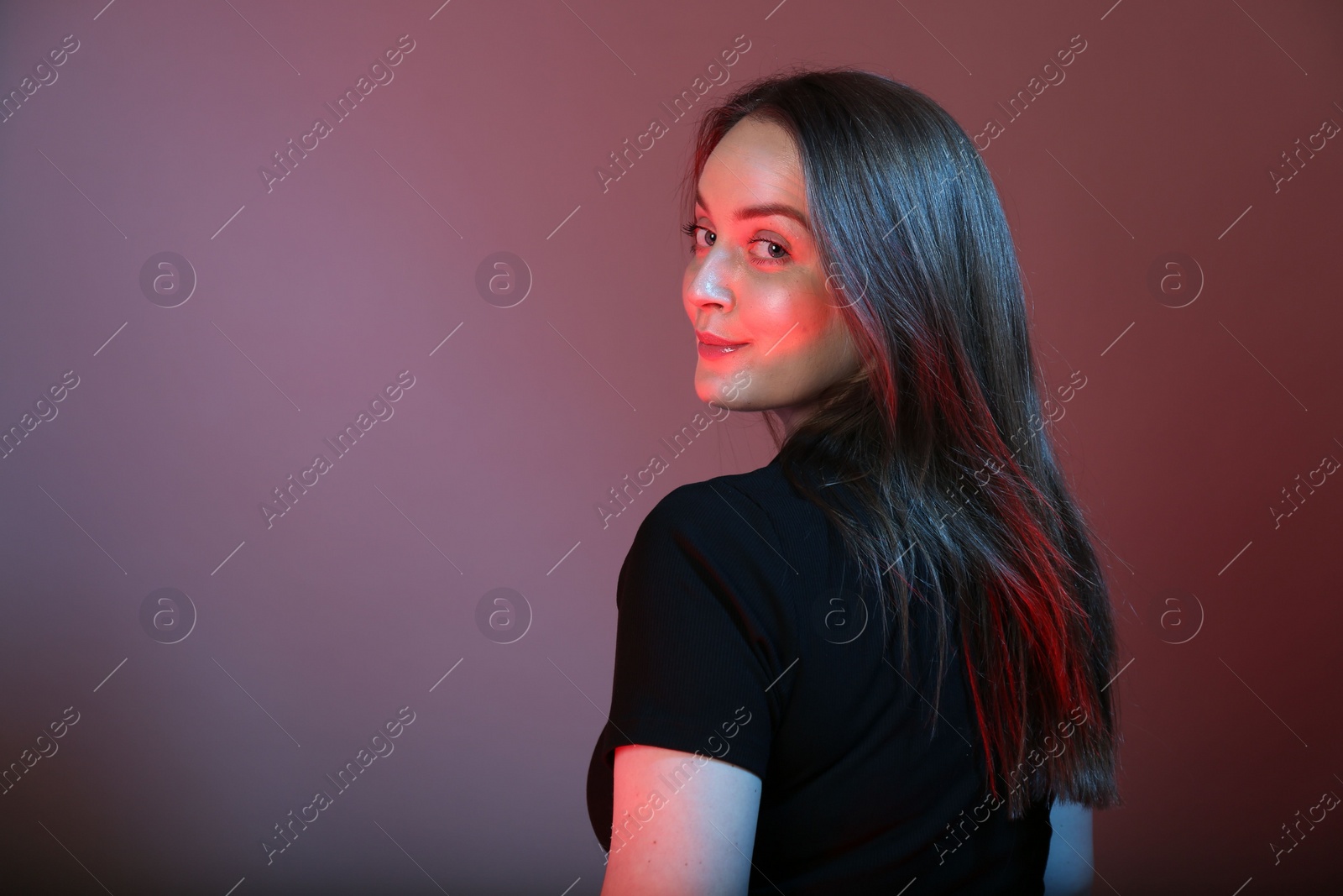 Photo of Portrait of beautiful young woman on color background with neon lights. Space for text