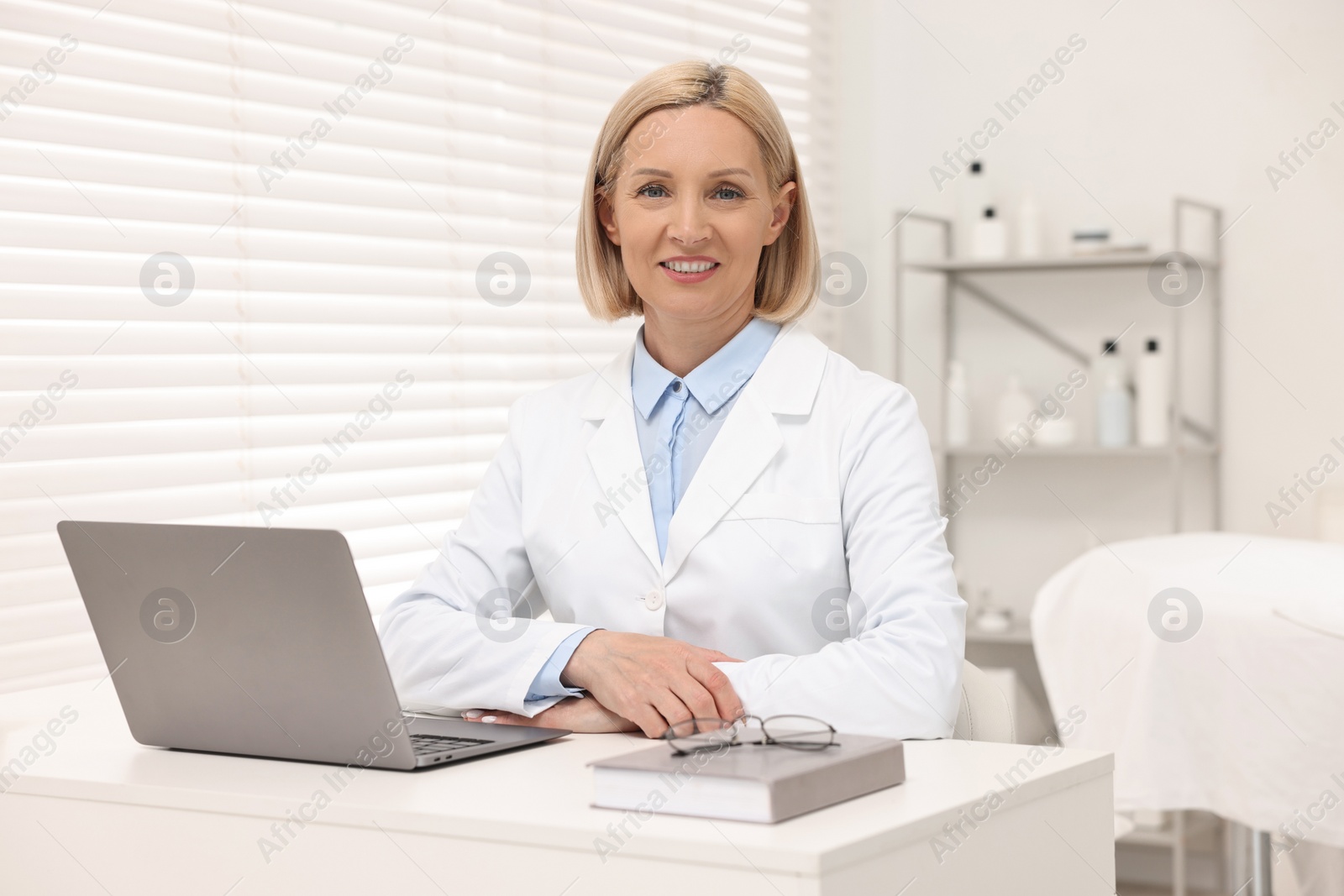 Photo of Portrait of happy dermatologist at white table in clinic