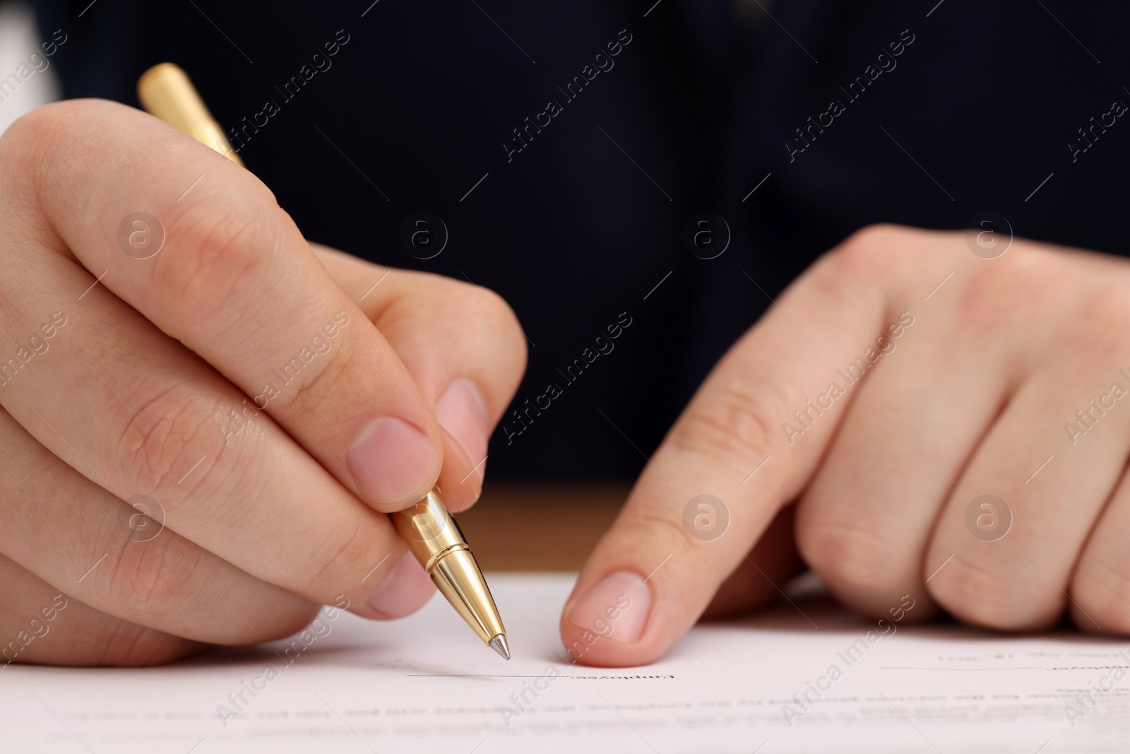 Photo of Man signing document at table, closeup view