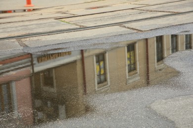 Photo of Reflection of beautiful building in puddle on asphalt outdoors