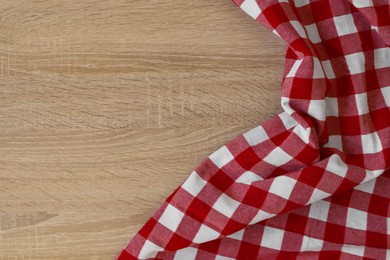 Photo of Checkered picnic cloth on wooden table, top view. Space for text