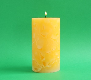 Alight scented wax candle on color background