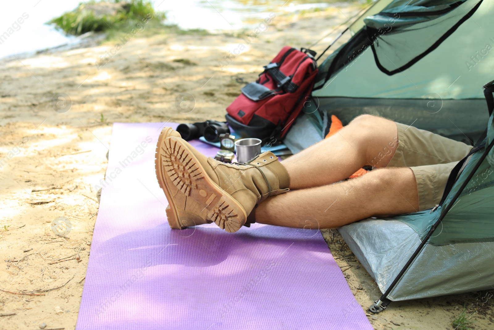 Photo of Young man resting in camping tent on riverbank, closeup. Space for text