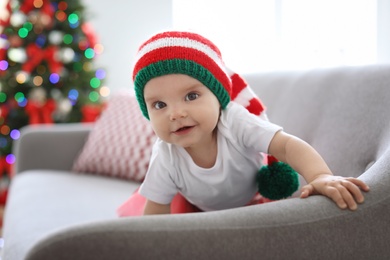 Photo of Cute baby in Christmas costume on sofa at home