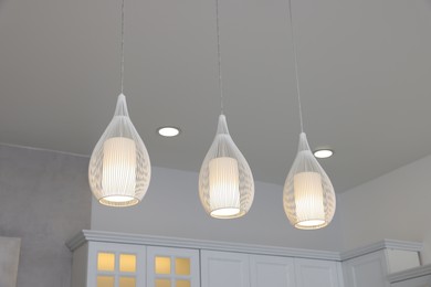 Ceiling with modern lamps and furniture in stylish kitchen, low angle view