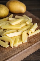 Photo of Whole and cut raw potatoes on wooden table, closeup