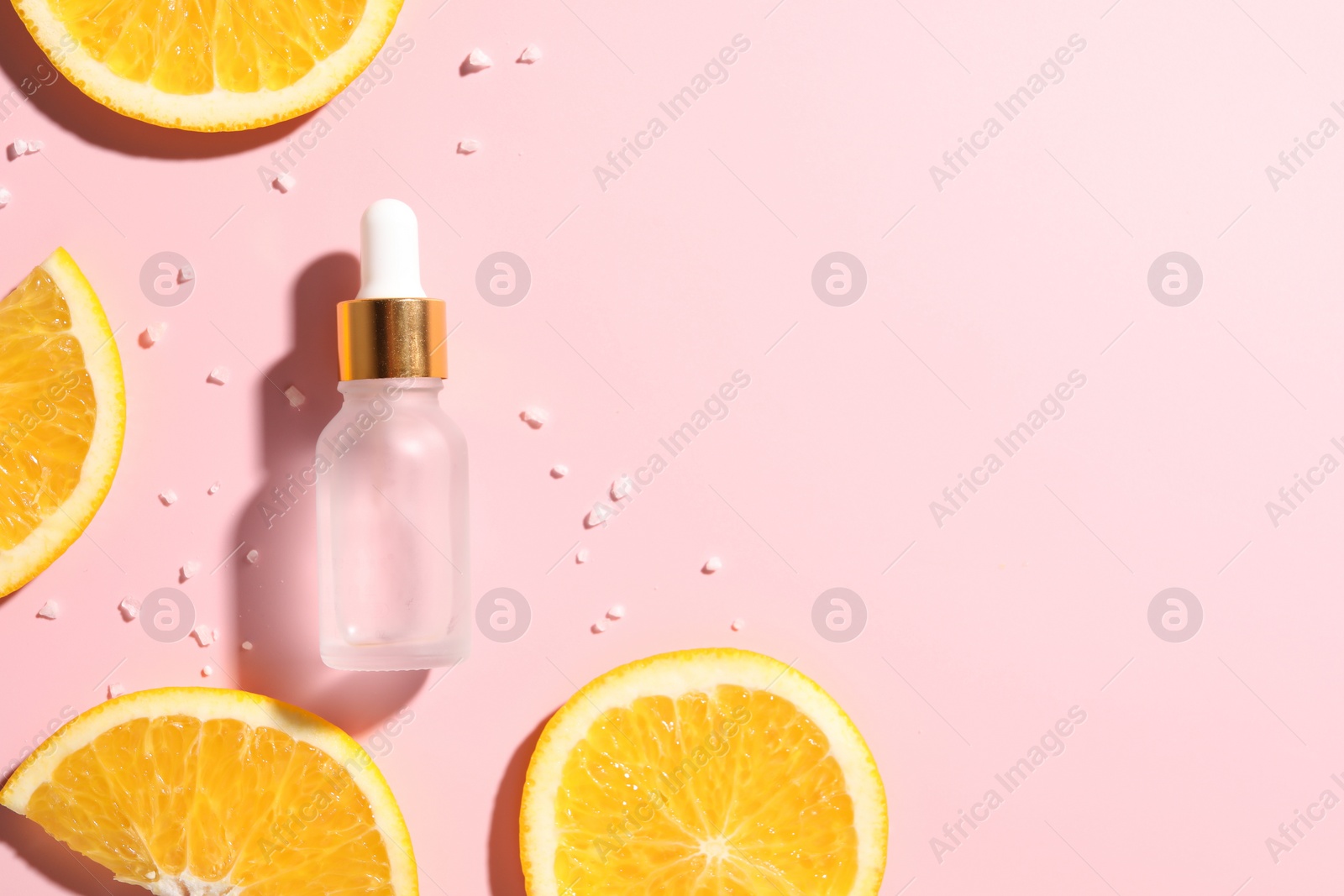 Photo of Bottle of cosmetic serum and orange slices on pink background, flat lay. Space for text