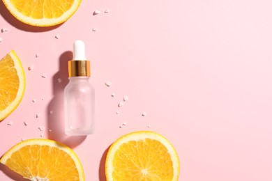 Bottle of cosmetic serum and orange slices on pink background, flat lay. Space for text