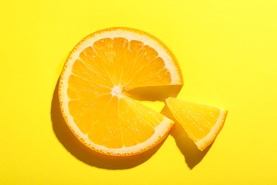 Photo of Slices of juicy orange on yellow background, top view