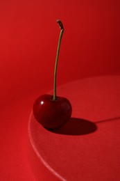 Photo of Sweet ripe cherry on red table against color background