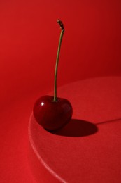 Sweet ripe cherry on red table against color background