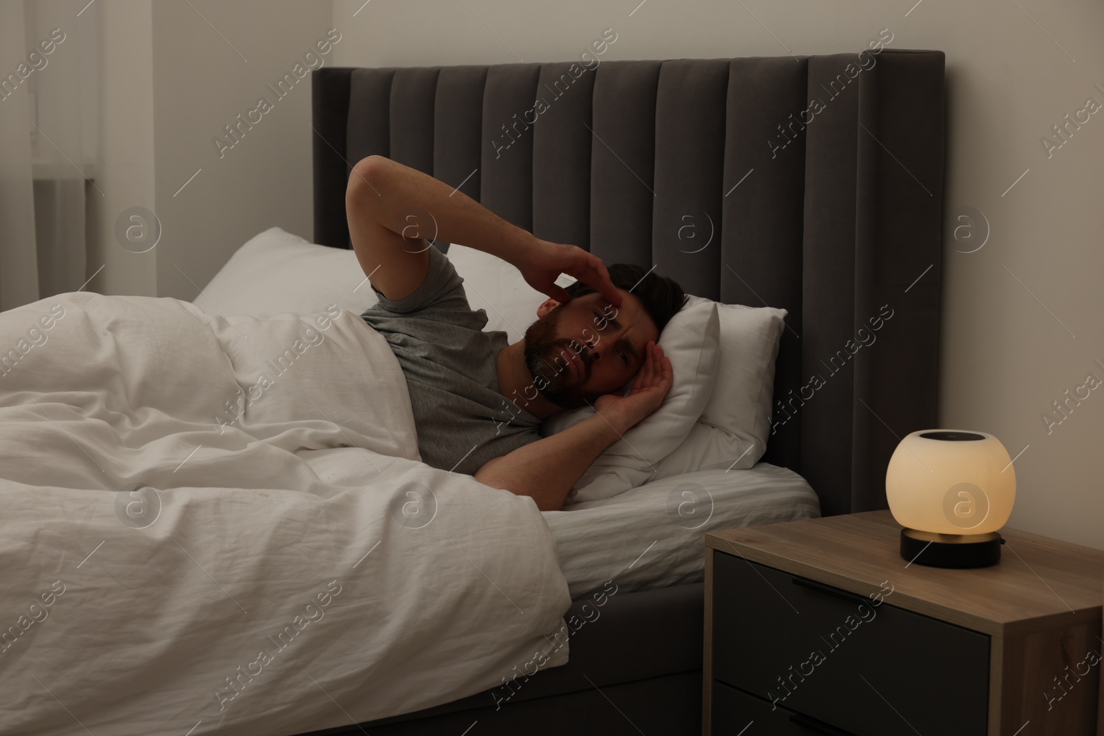 Photo of Man suffering from headache in bed at night