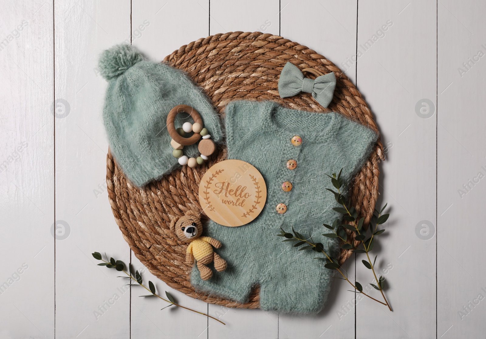 Photo of Children's clothes, toys and green plant on white wooden table, top view